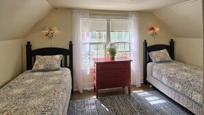 Un dormitorio con dos camas, un aparador y una ventana con cortinas.