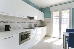 Een moderne keuken met witte kastjes, een ingebouwde oven en een koffiezetapparaat.