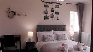A bedroom with a bed, bedside lamps, a wall-mounted photo collage, and a window with curtains. - Wagtail Lodge Boutique Country House B&B, Stonehaven (Stonehaven)