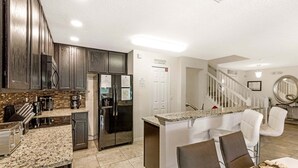 A modern kitchen with dark wood cabinets, a stainless steel refrigerator, and a granite countertop.