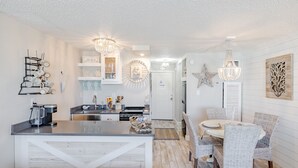 Een moderne keuken met een centraal eiland, witte kasten en hanglampen.
