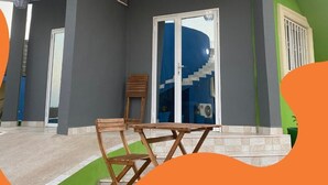 A modern building with a grey exterior, a glass door entrance, and a staircase leading to a covered area. - Amazing Seaview Room | Cape Point, Bakau (Bakau)