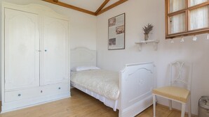 Een slaapkamer met een bed, een stoel, een kledingkast en een raam.