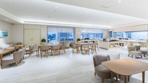 Ein moderner Hotel-Speiseraum mit verschiedenen Sitzgelegenheiten, einer Küchenzeile und großen Fenstern mit Blick.