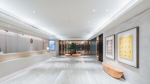 Eine moderne Hotelhalle mit Empfangstresen, Sitzgelegenheiten und gerahmten Kunstwerken an den Wänden.