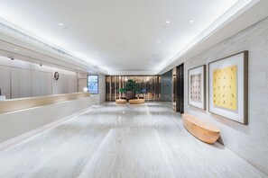 Un vestíbul d'hotel modern amb una recepció, zona de seients i obres d'art a les parets.