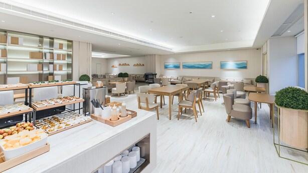 Eine moderne Hotelhalle mit einem Buffetbereich, Sitzgelegenheiten und Kunstwerken an den Wänden.