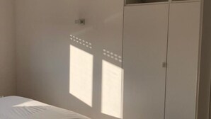 Ein Schlafzimmer mit Bett, Kleiderschrank und Lichtschalter an der Wand.