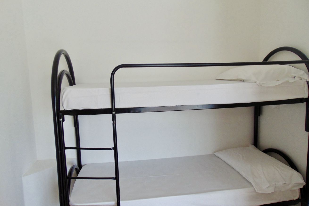 Un lit superposé avec une échelle, un matelas blanc et un oreiller sur le lit du haut.