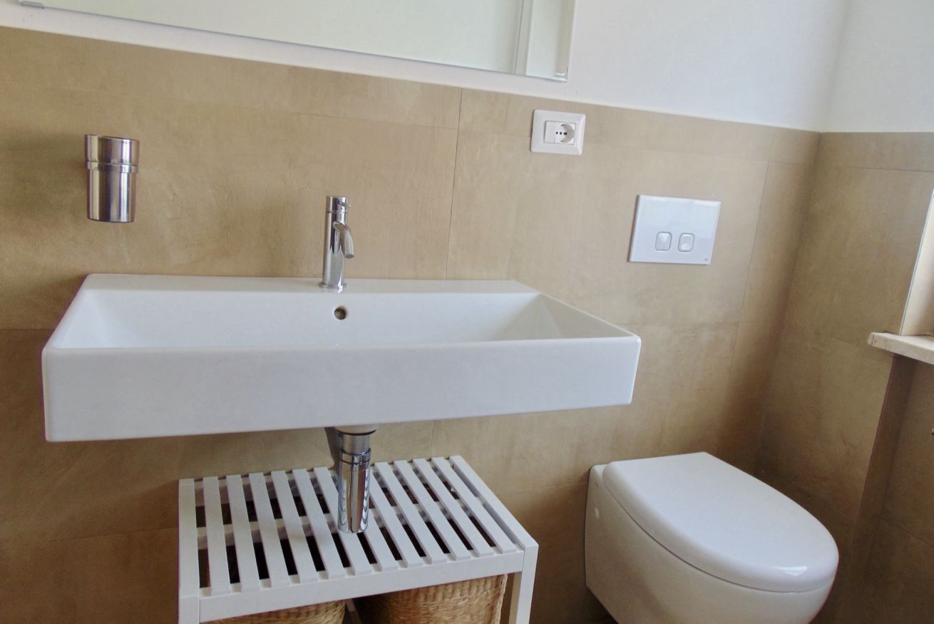 A bathroom with a white sink, a toilet, and a mirror above the sink.