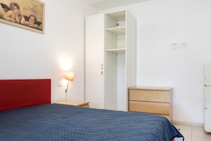 A bedroom with a bed, a wardrobe, a nightstand, and a lamp.