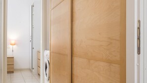 A laundry area with a washing machine, a wooden wardrobe, and a small bedside table with a lamp. - M273 - Marcelli, new three-room apartment with garden (Marcelli)