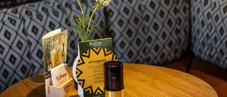Una mesa de madera con un menú, un florero con flores y una vela.