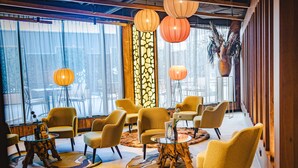 Een moderne zithoek met gele stoelen, een glazen salontafel en decoratieve lantaarns.