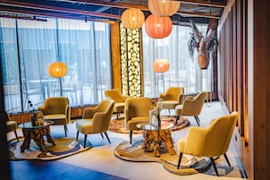 Un área de descanso moderna con sillas amarillas, una mesa de centro de vidrio y faroles decorativos.
