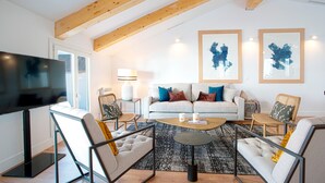 A modern living room with a sofa, armchairs, a coffee table, and a flat-screen TV.