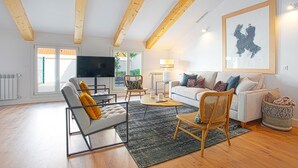 A modern living room with a sofa, chairs, a coffee table, and a TV.