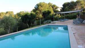 A rectangular swimming pool with a tiled edge, surrounded by lounge chairs and a covered seating area. - Apartment Cala Anguilla  (Manacor Cala Anguila)