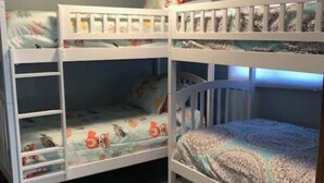 Quarto com beliches, tapete estampado e luminária no teto.