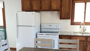 Uma cozinha com armários de madeira, uma geladeira branca, um fogão e uma mesa de jantar com cadeiras.