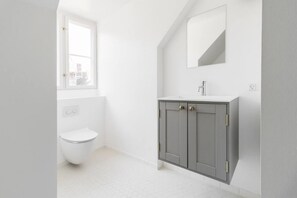 A bathroom with a toilet, a sink, and a mirror. - 175sqm High-end Luxury Apartment - Heart of CPH (Copenhagen)