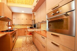 A modern kitchen with wooden cabinets, stainless steel appliances, and a central island with seating. - Fortuny 3967 Luxury Suites Wine - Ve-l736-sanm3967at (Venice)