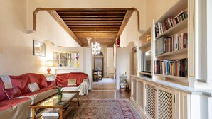 A living room with a red sofa, a coffee table, and a bookshelf. - Fortuny 3967 Luxury Suites Wine - Ve-l736-sanm3967at (Venice)