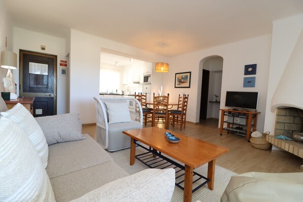 A living room with a sofa, a dining table, chairs, a TV, and a fireplace.