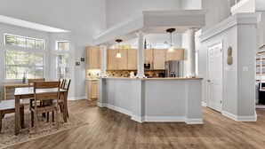 Une cuisine spacieuse dotée d’un îlot central, de meubles en bois et de luminaires suspendus.
