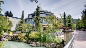 A hotel with a pool, surrounded by greenery and a stone wall. - ❄️ Whistler Center 1BR:Walk Everywhere. Free Parking. Fire, Sleeps 4 ❄️ (Whistler)