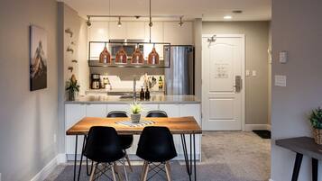 Une cuisine moderne dotée d’un îlot central, d’appareils électroménagers en acier inoxydable et de luminaires suspendus.