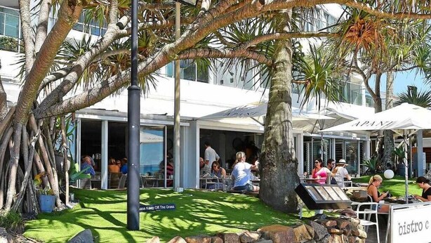 Un espace extérieur aménagé pour les repas, avec des murs en pierre, des palmiers et des parasols.