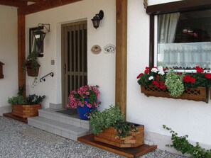 Una casa con porche de madera, una puerta y una ventana con jardineras.