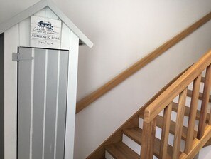 Una escalera de madera con peldaños y una puerta blanca con un letrero encima.
