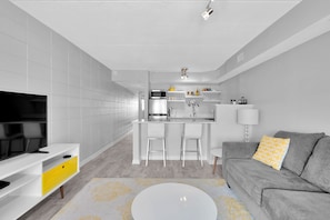 Relax in a stylish space with a comfortable sofa, flat-screen TV, and a compact kitchen area.