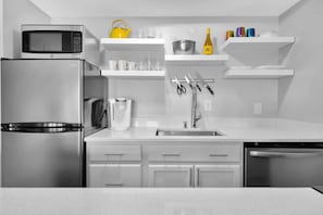 Fully equipped kitchen with a refrigerator, microwave, and dishwasher, along with ample storage and counter space.