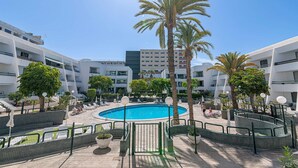 A pool area with palm trees, lounge chairs, and a clear blue sky. - GO2TENERIFE Apart'Arona City center & Beach at 5 min (Playa de las Américas)