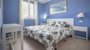 A bedroom with a bed, nightstands, a desk, and a window with curtains. - GO2TENERIFE Apart'Arona City center & Beach at 5 min (Playa de las Américas)