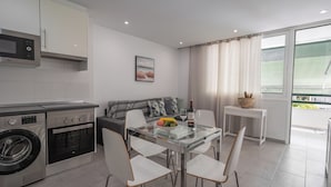 A modern kitchen with stainless steel appliances, a glass dining table, and a view of the outdoors.