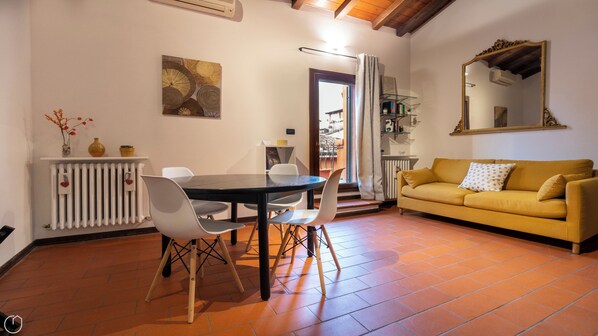 A dining area with a table and chairs, a sofa, and a radiator. - Piella 5 - One Bedroom Apartment, Sleeps 4 (Bologna)