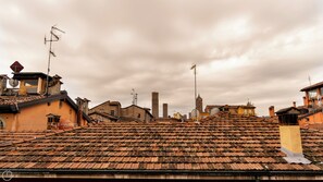 A rooftop with terracotta tiles, a brick building, and a tower in the background. - Piella 5 - One Bedroom Apartment, Sleeps 4 (Bologna)