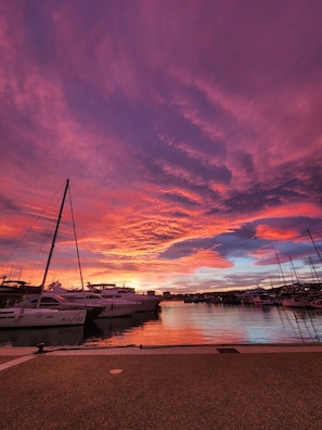 A marina with boats docked, a clear sky, and a sunset.