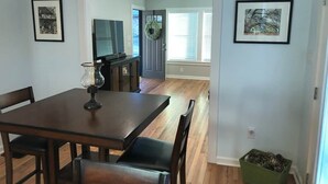Un comedor con una mesa y sillas de madera, una lámpara de mesa pequeña y una planta verde en el suelo.