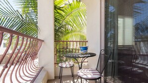A balcony with a metal railing, a small table with two chairs, and a window with blinds. - Beautiful By the Beach/King bed/AC/2 car garage (San Diego)