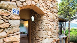 Un edificio de piedra con un letrero numerado, una entrada con arco y vistas a un jardín y al mar.