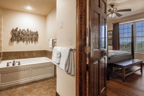 A bathroom with a bathtub, a wooden bench, and a view of the outdoors through a window. - Great Location! 2br/2ba Beautiful Views Indoor/Outdoor Pools, Game Room 3003 (Pigeon Forge)