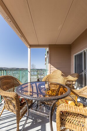 A covered balcony with wicker furniture and a glass table. - Great Location! 2br/2ba Beautiful Views Indoor/Outdoor Pools, Game Room 3003 (Pigeon Forge)