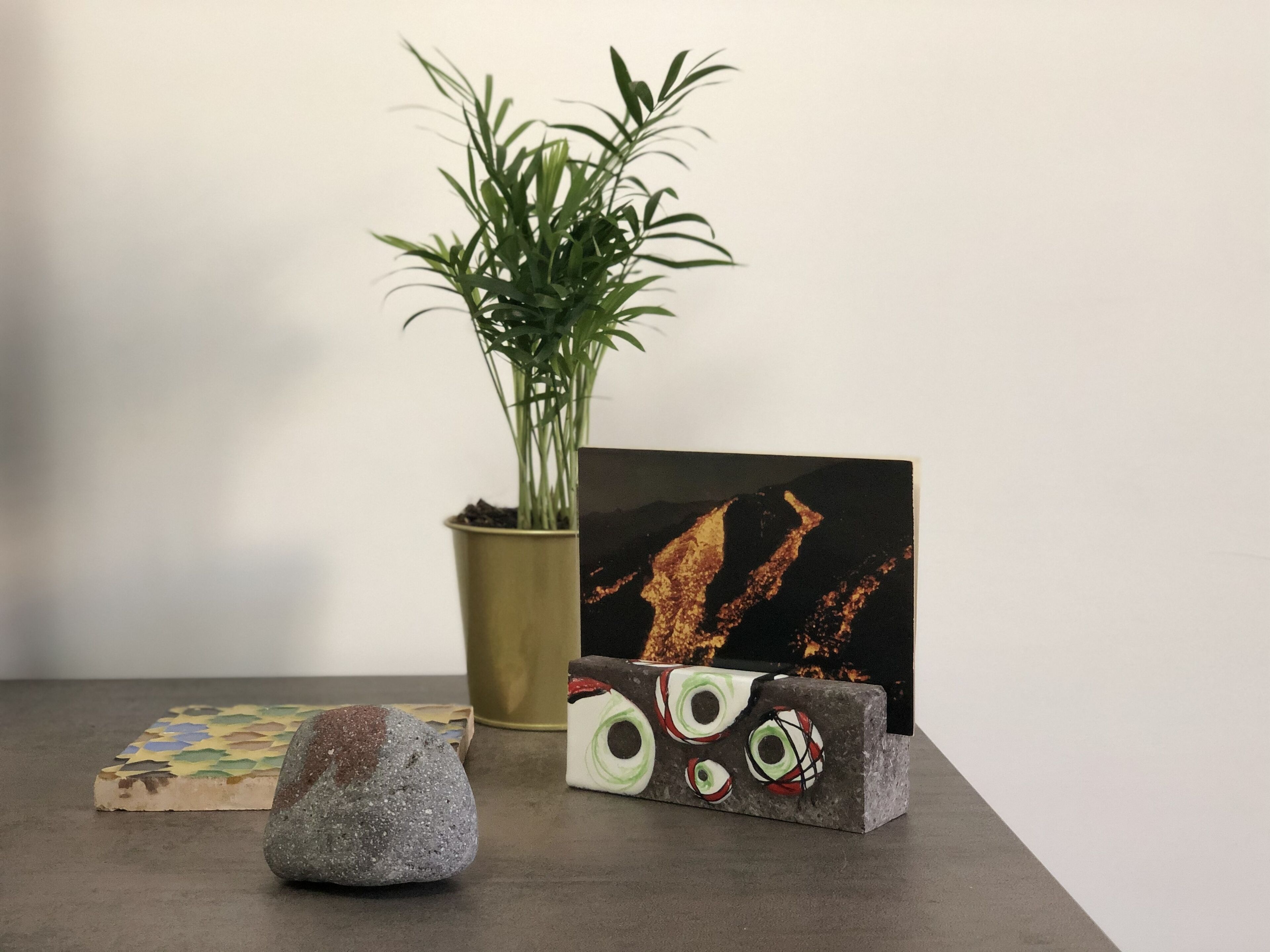 A table with a potted plant, a framed artwork, and a decorative stone.