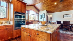 Eine Küche mit Holzschränken, einer Granit Arbeitsplatte, einem eingebauten Backofen und einem Essbereich mit Tisch und Stühlen.