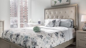 A bedroom with a large bed, a world map on the wall, and a view of buildings outside.